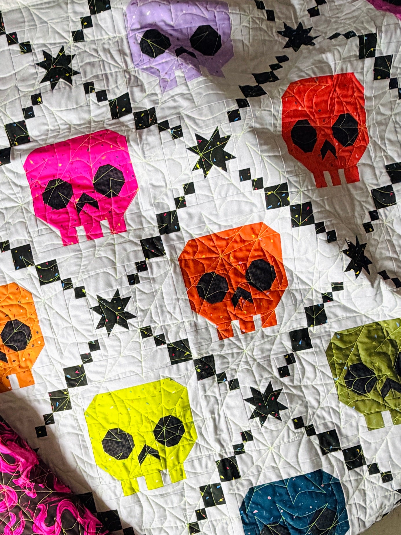 Bone Brigade quilt pattern by Libs Elliott featuring a rainbow of skulls in an Irish Chain layout.