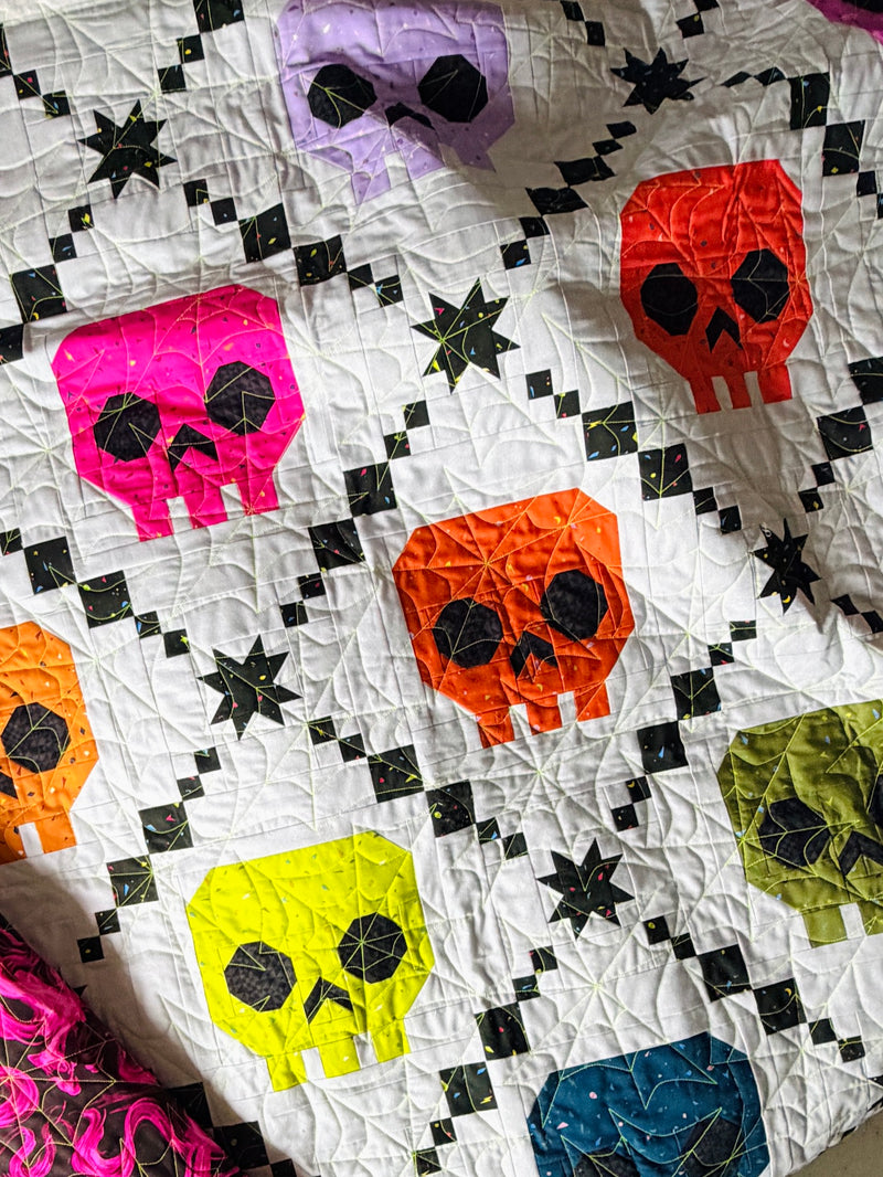 Bone Brigade quilt pattern by Libs Elliott featuring a rainbow of skulls in an Irish Chain layout.