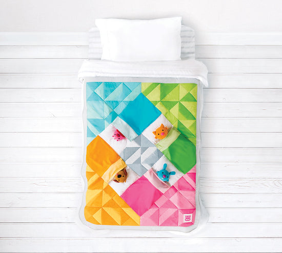 Colorful geometric patterned quilt with a white pillow on a wooden surface