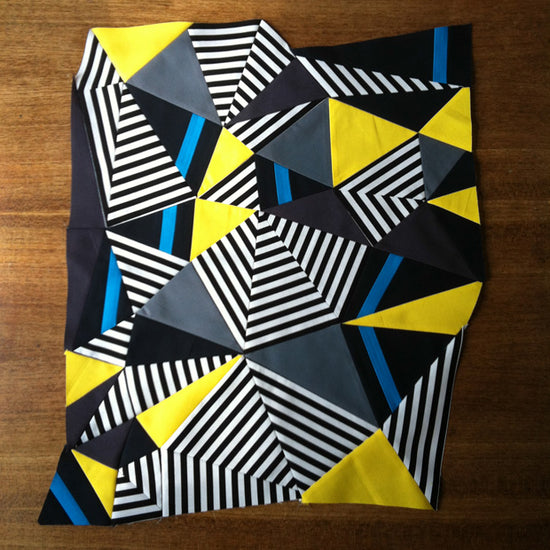 Geometric patterned fabric with black, yellow, blue, and white on a wooden surface